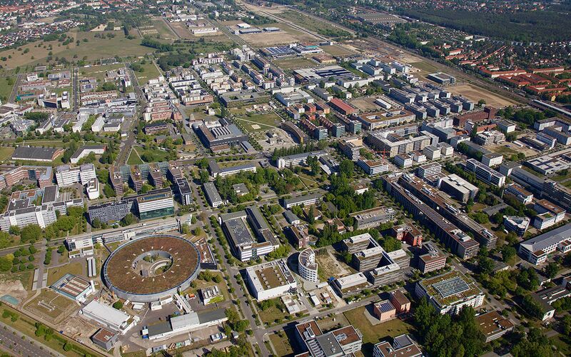 Luftbild von Adlershof zeigt das weitläufige Gelände mit Gebäuden und Grünflächen, aufgenommen im Mai 2019.