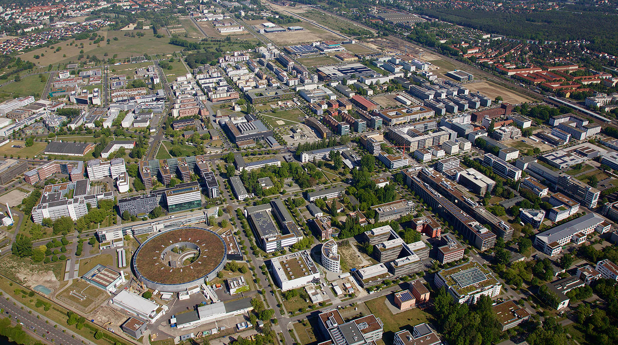 Luftbild von Adlershof zeigt das weitläufige Gelände mit Gebäuden und Grünflächen, aufgenommen im Mai 2019.